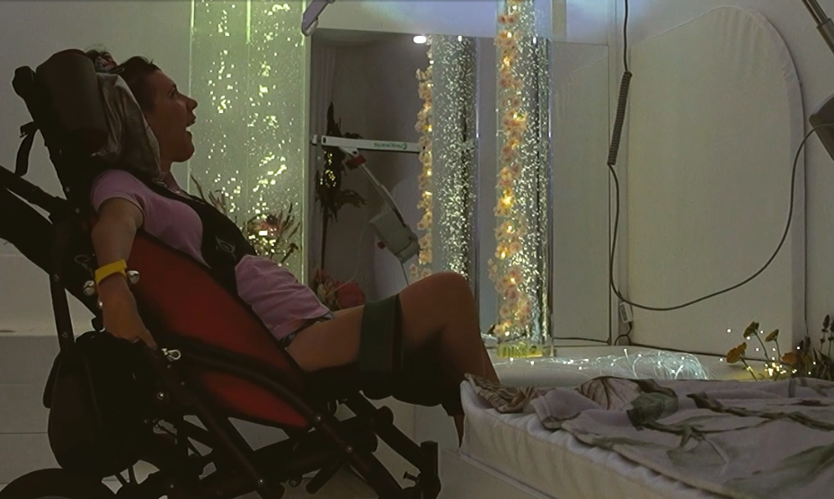 Uczestniczka zajęć w sali doświadczania świata w ŚDS Wejherowo obserwuje kolorowe światła podczas sesji Snoezelen.